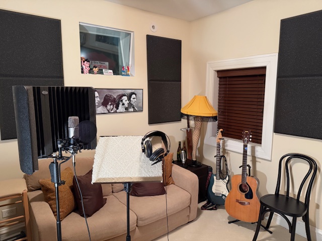 Voice studio with microphone, music stand, headphones, and guitar