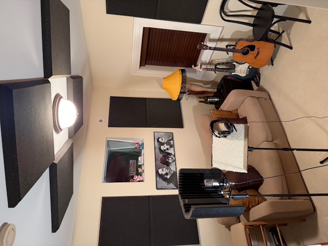 Voice studio with microphone, music stand, and headphones with sound panels on ceiling