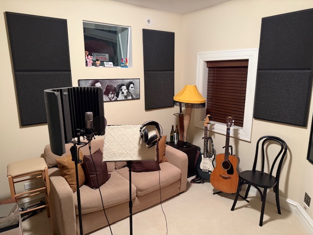 Voice studio with microphone, music stand, headphones, and guitar